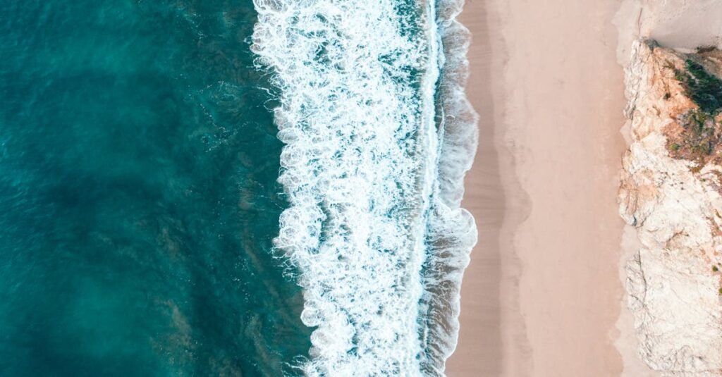Stunning aerial view of ocean waves hitting a sandy beach in Los Angeles, California.